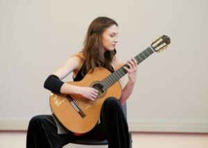 Kalina Polańska siedząca i grająca na gitarze